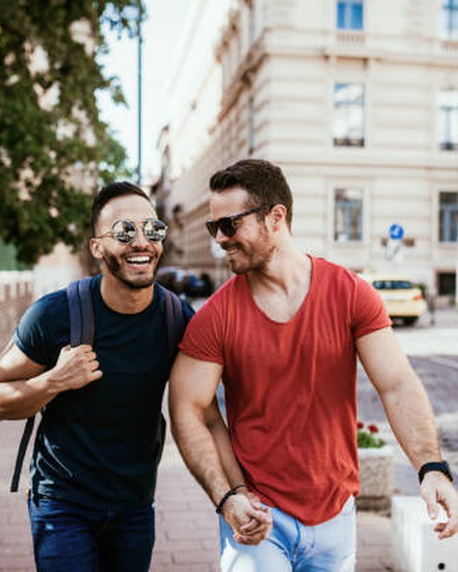 Two travellers laughing as they walk down a sunlit European street